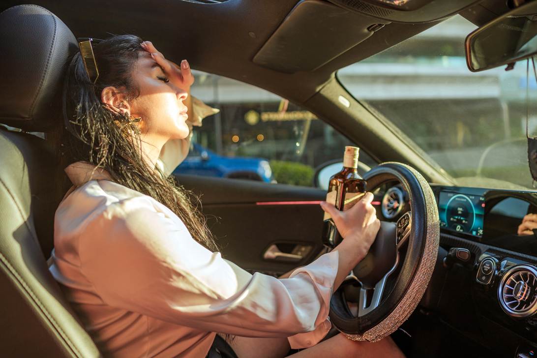 A person holding a bottle in her hand while driving

AI-generated content may be incorrect.
